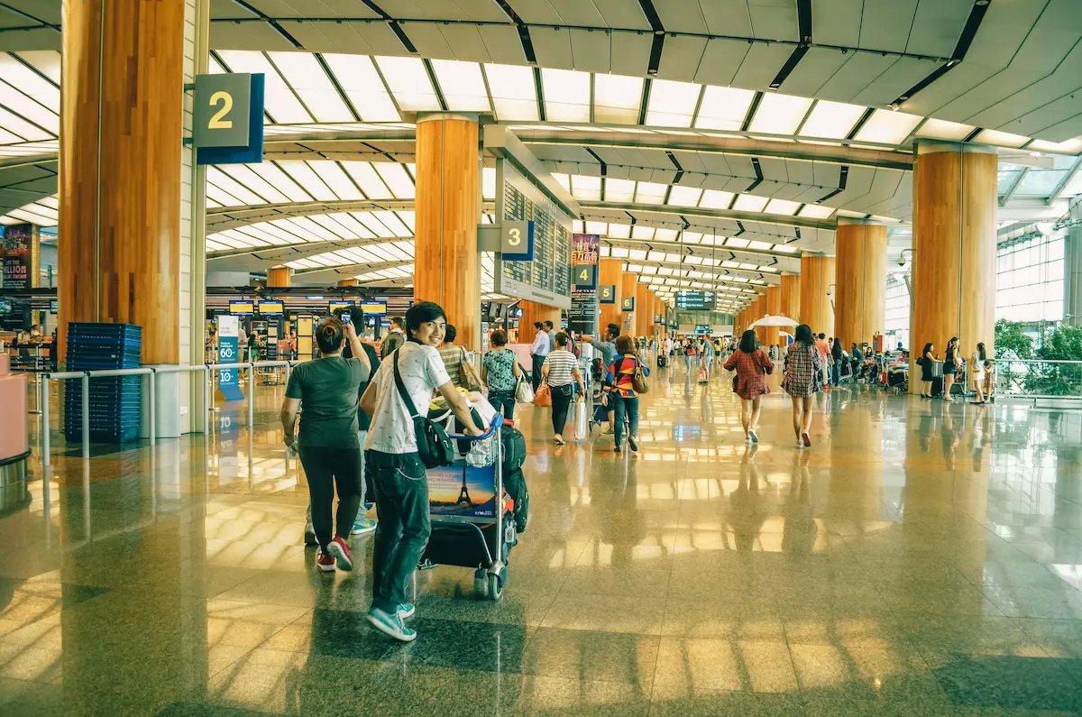 Travelers moving through an airport terminal with luggage